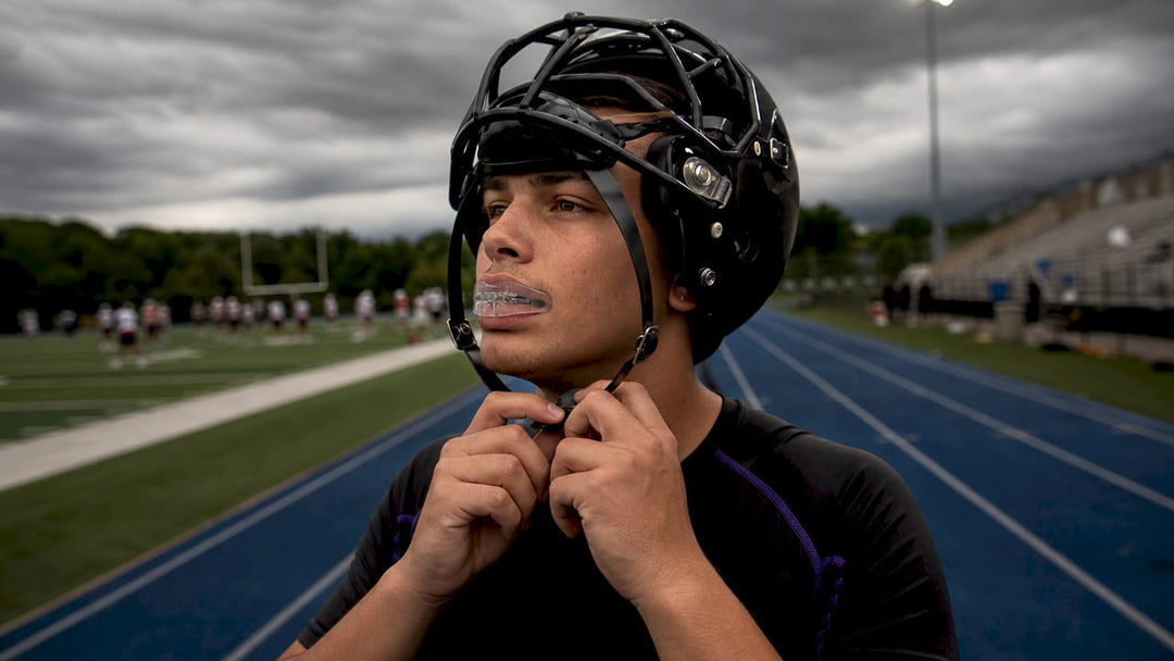 Athlete putting on mouth guard on football field