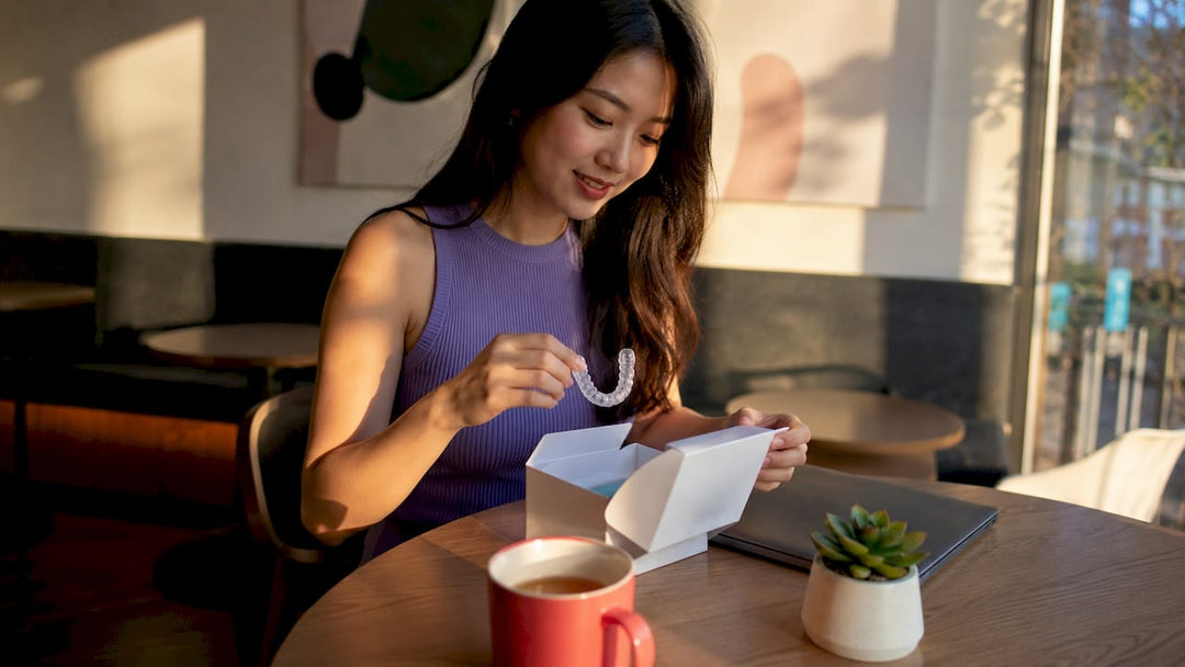 Woman unboxing dental retainer package at kitchen table