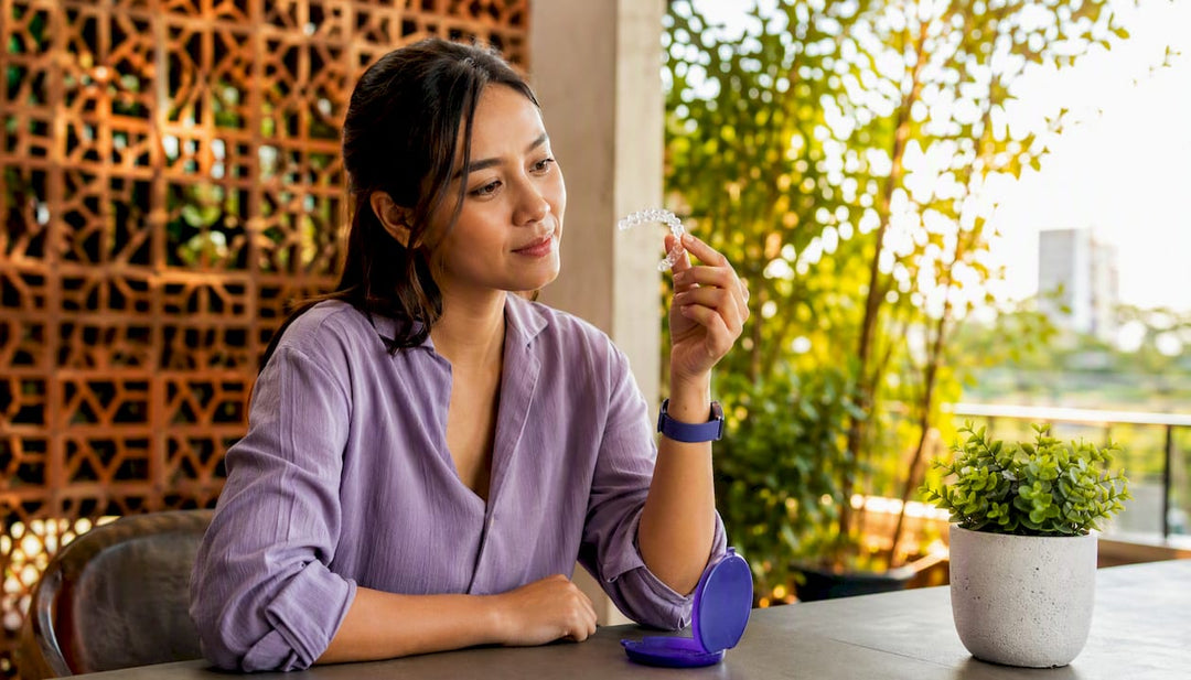Woman inspecting clear dental retainer at home