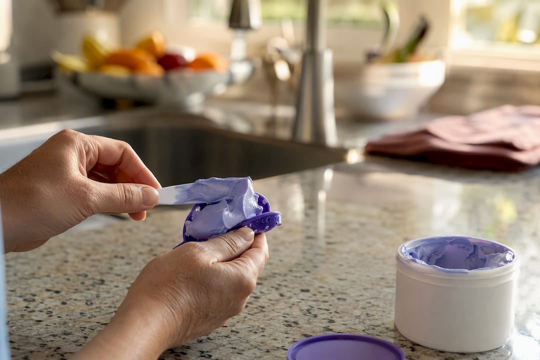 Hands filling dental impression tray with putty